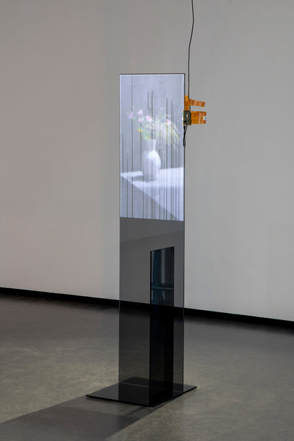 Weil es das Objekt von seiner räumlichen und zeitlichen Bindung löst, ist der digitale Screen das moderne Präsentationsmedium schlechthin. Dabei scheint es beinahe so, als würde das Glas des Screens die Vase in sich einschließen. Anstelle ihrer Oberfläche berühren wir Glas. Der Effekt einer von Wasserdampf beschlagenen Fensterscheibe spielt auf die Transparenz der Barriere an: erst, wenn sich Sonnenlicht in ihr spiegelt oder Wasserdunst sich auf ihr niederschlägt, wird sie in ihrer Transparenz durchschaubar und als Barriere erkannt. Streicht man mit dem Finger über das Glas des Touchscreens, wird der virtuelle Dunst beiseite gewischt und gibt den Blick frei auf das dahinter liegende Bild der Vase.