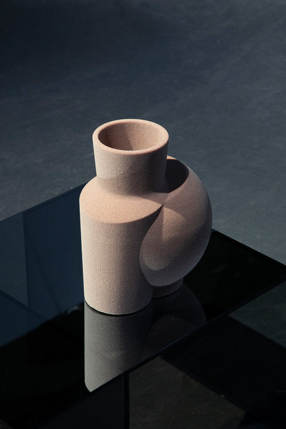 Die Vase wird digital in all ihre Ebenen und Bestandteile zerlegt. Materialität, genauso wie Größe und Form, sind nunmehr variabel. Sie muss keiner Funktion gerecht werden. Durch die Übertragung zurück ins Analoge kommen den einzelnen Ebenen neue Funktionen zu: Die Textur wird zum Material, aus dem die Vase besteht. Es entsteht eine analog-digitale Skulptur, eine Collage aus Körper und Fläche – ein Hybrid aus Bild und Objekt. Die Collage eröffnet einen Zwischenraum(f), in dem sich die Vase in ihrem transformierten Äußeren präsentiert, lediglich die Reflexion lässt sie in ihrer ursprünglichen Form erscheinen. Es werden so Qualitäten aus beiden Welten verflochten. Die Skulptur findet Platz auf einem Sockel aus Glas, von dem sie getragen, jedoch nicht mehr verdeckt wird.